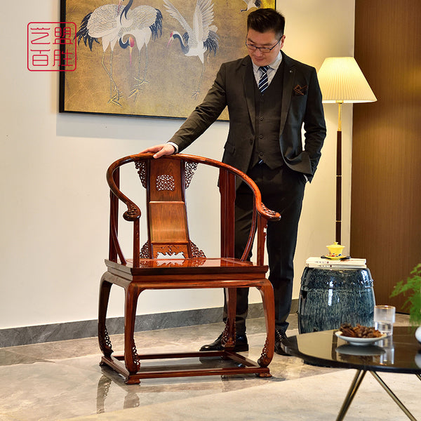 Man standing next to a finely carved Huanghuali circle chair in a modern setting