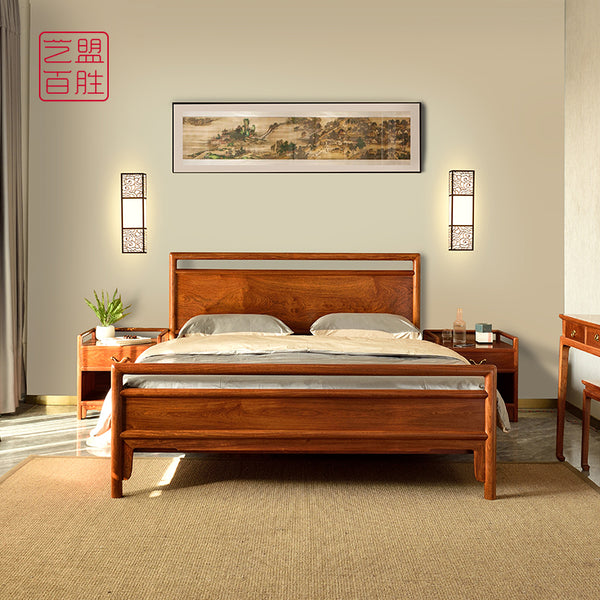 A large plain rosewood bed with matching bedside tables.