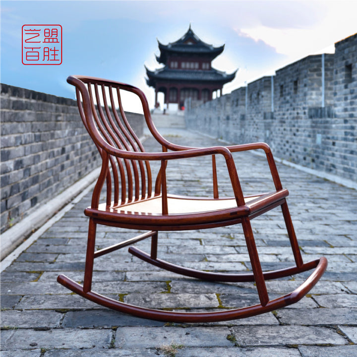 A large rosewood rocking chair with a curved backrest